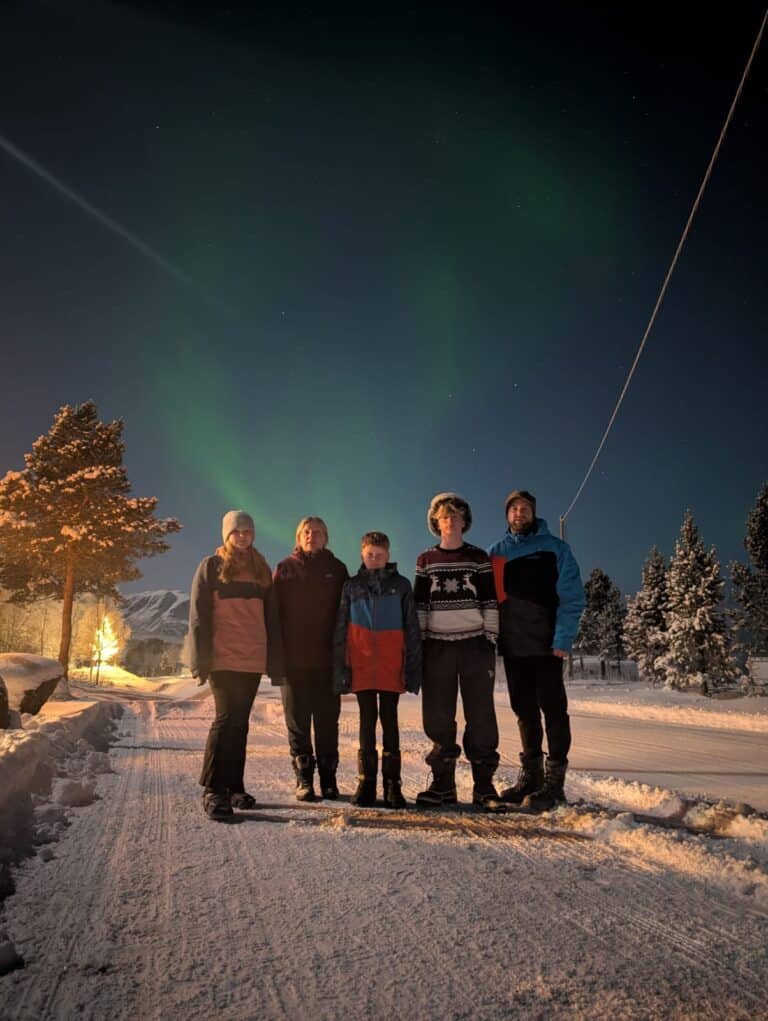 Familie kijkt naar het noorderlicht op een winternacht.