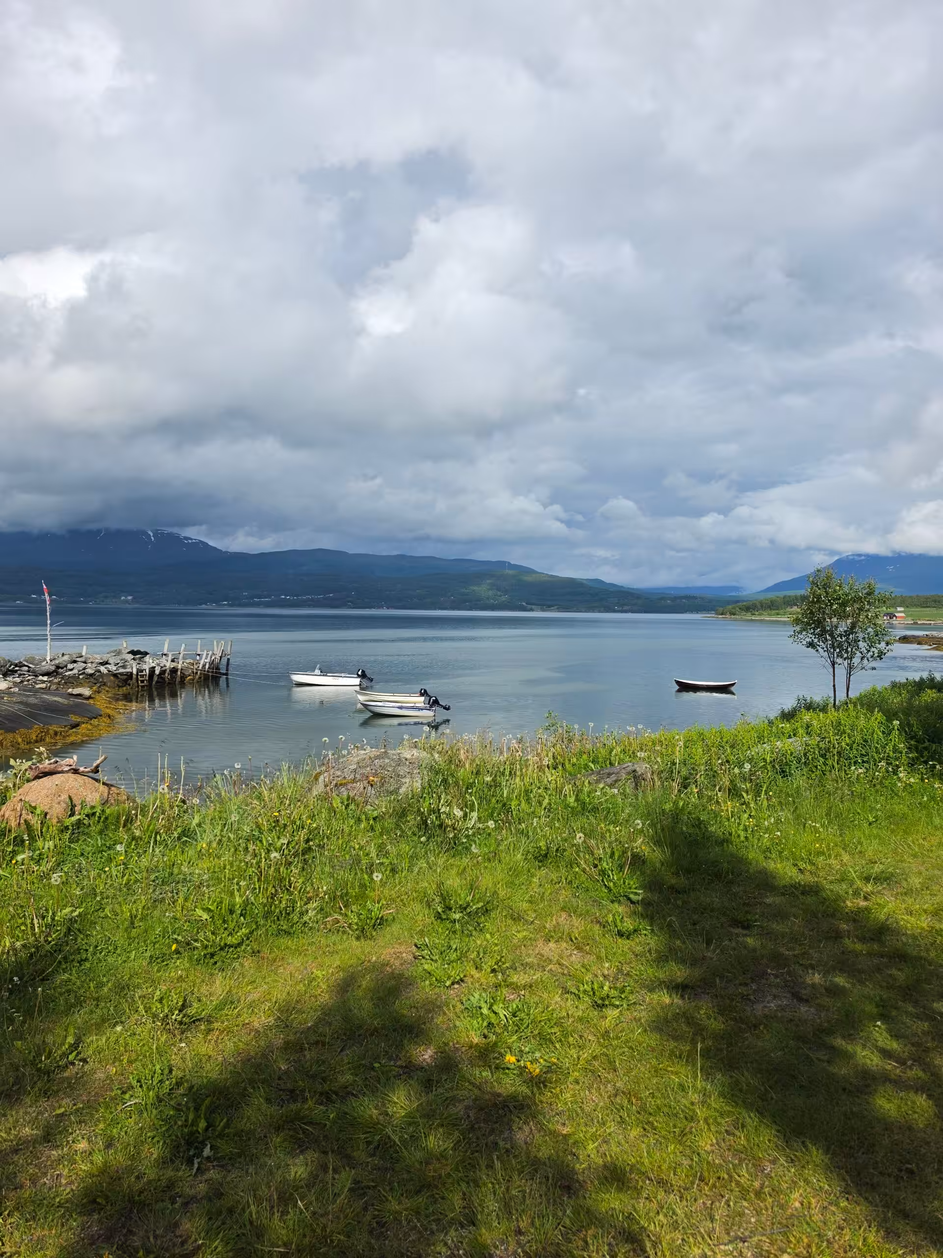 Ruhige Fjordlandschaft mit kleinen Booten und bewölktem Himmel