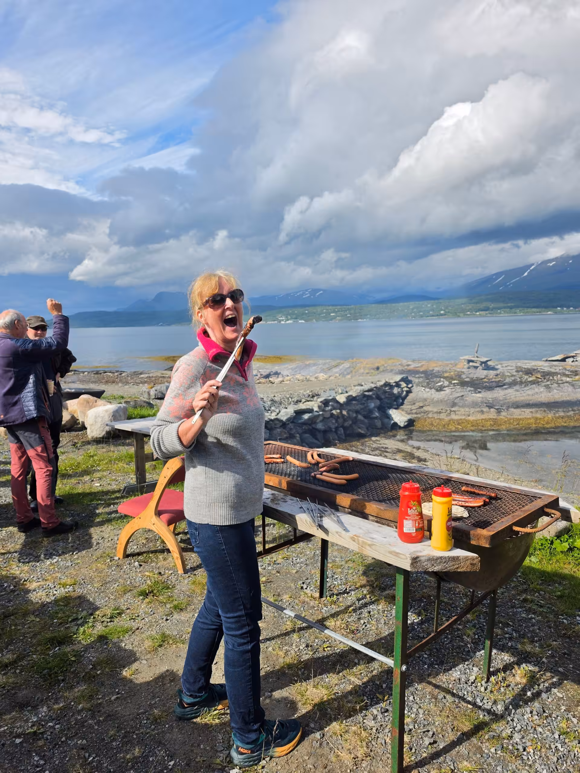 Grillen am Wasser mit Bergen und dramatischen Wolken im Hintergrund