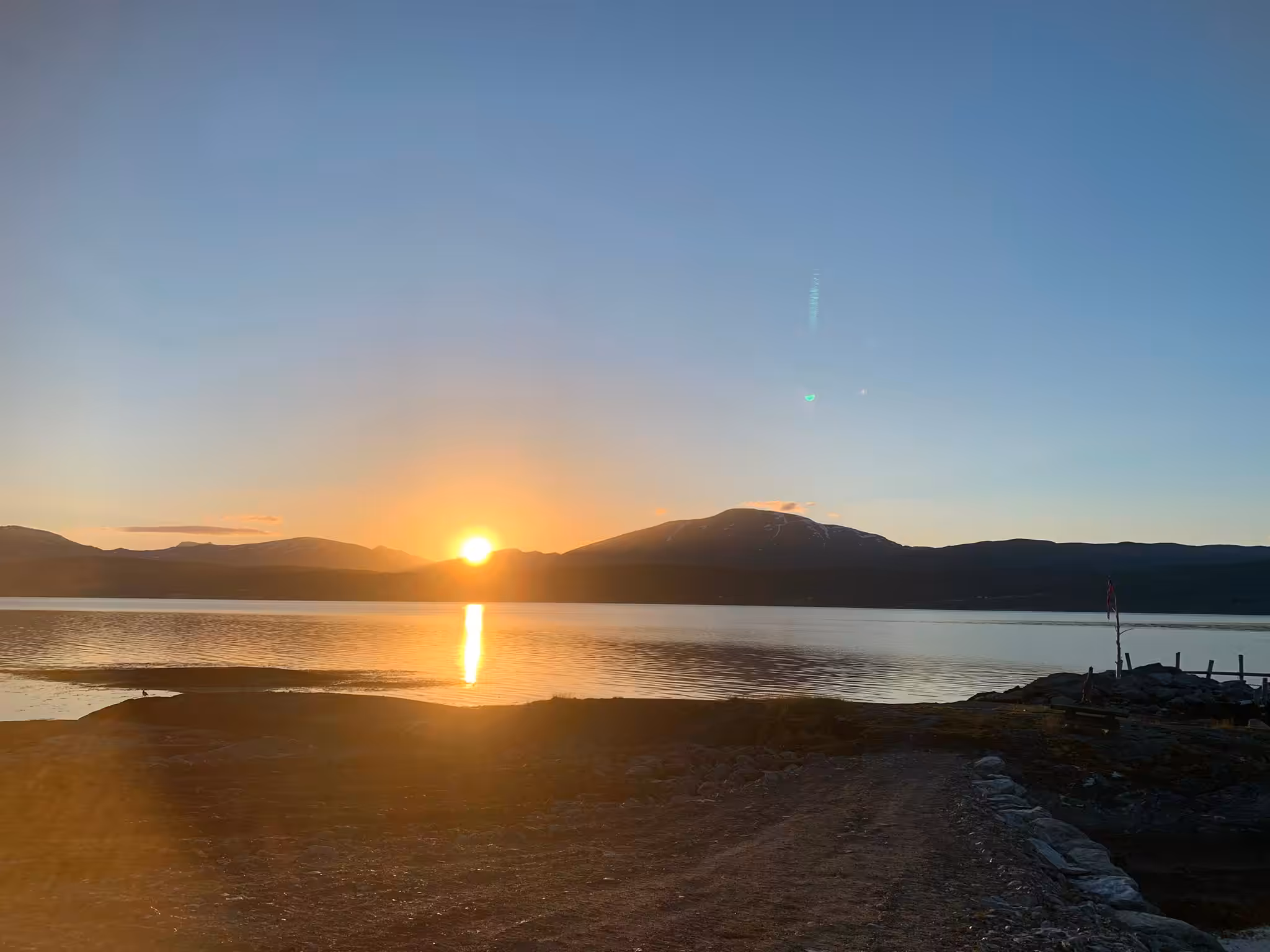 Sonnenuntergang über stillem Wasser und Bergen