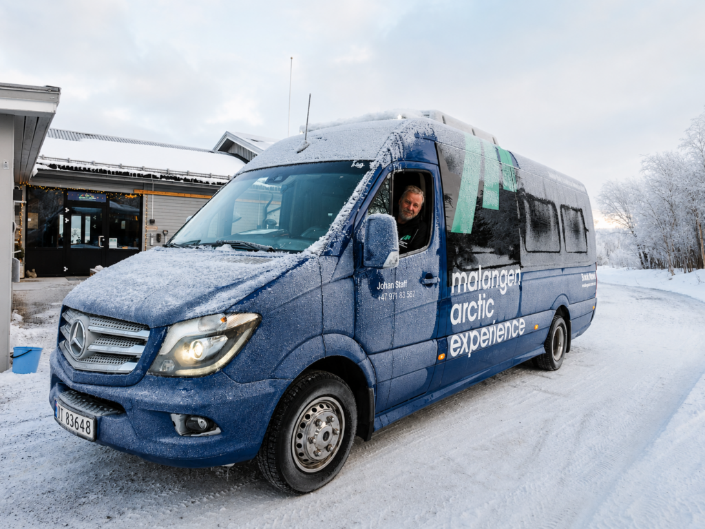 Snødekt minibuss med sjåfør i vinterlandskap